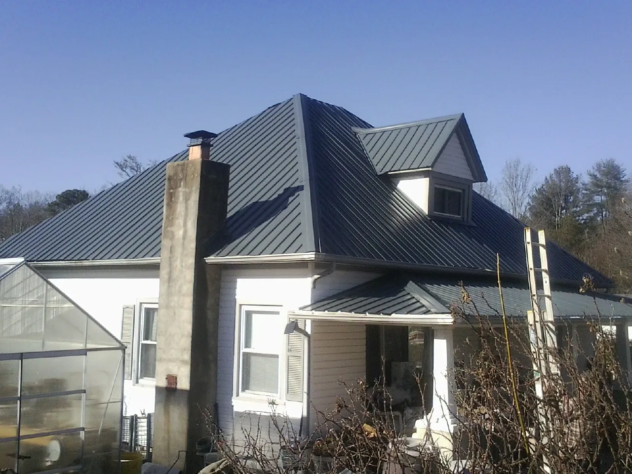 Dark blue standing seam metal roof on a white farmhouse with dormer — Slate & Tile Roof Repair by Roofing Brothers in Mount Tremper