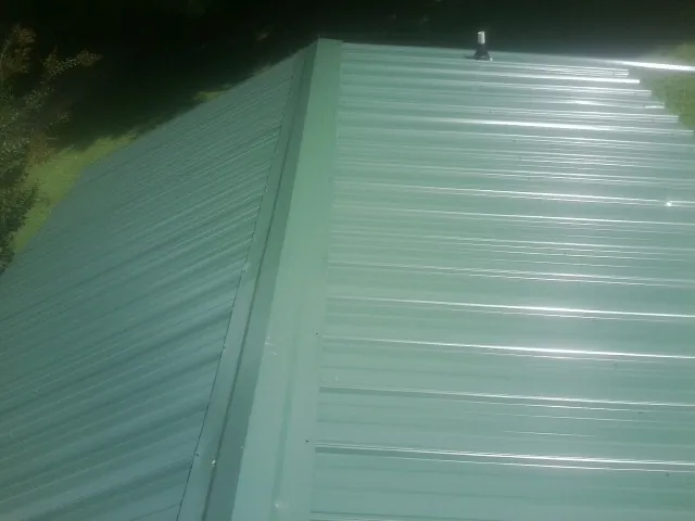 New green metal panels meeting at the ridge of a roof — Flat Roof Repair work by our crew in Mount Tremper