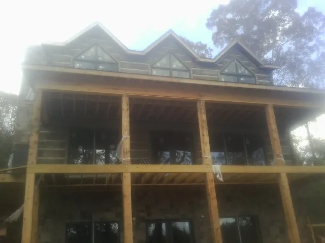 Dormers and porch framing on a large log home under construction — Roof Coating work by our crew in Mount Tremper