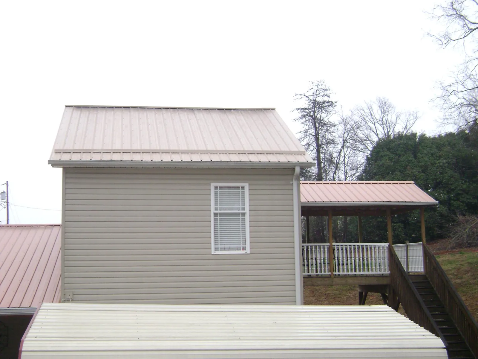 Tan metal roofs on a two story addition and attached porch, from a Roof Replacement job in Mount Tremper