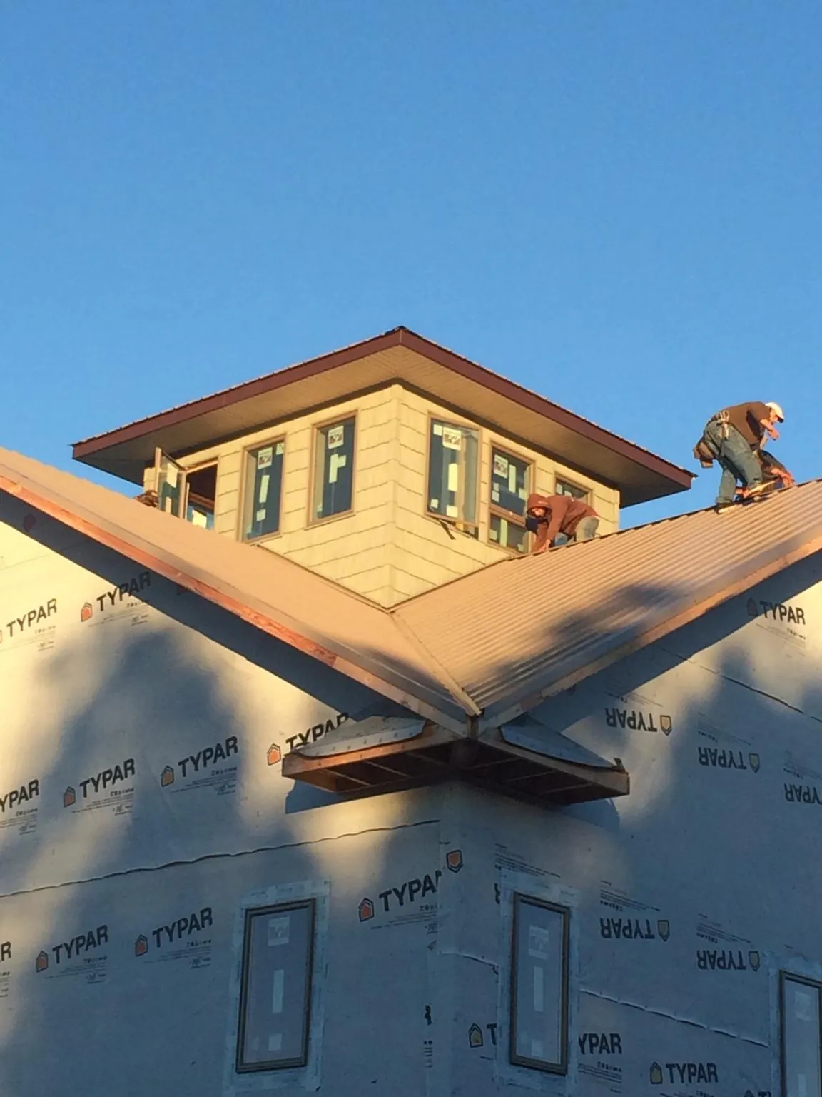 Roofers working around a rooftop cupola on a new metal roof at sunset — Roof Waterproofing in Mount Tremper by Roofing Brothers